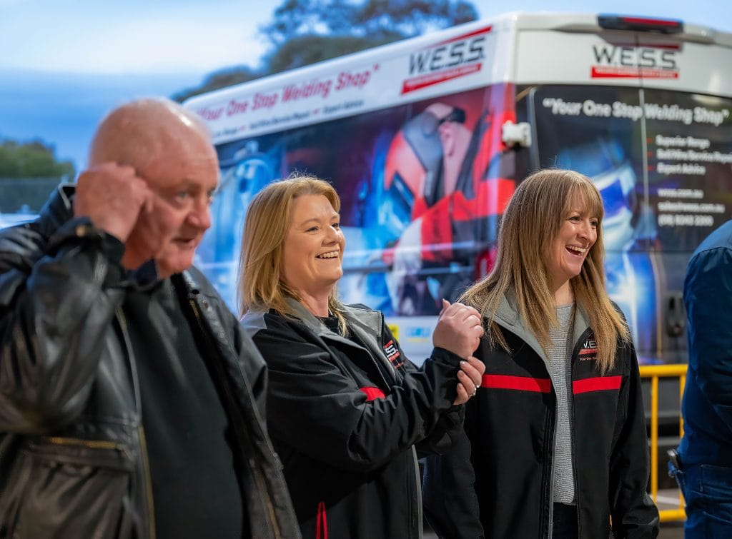 Attendees speaking at a trade show in Adelaide with branding in the background